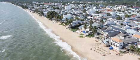A coastal town with beachfront properties, including houses and villas with balconies, some with attached patios.