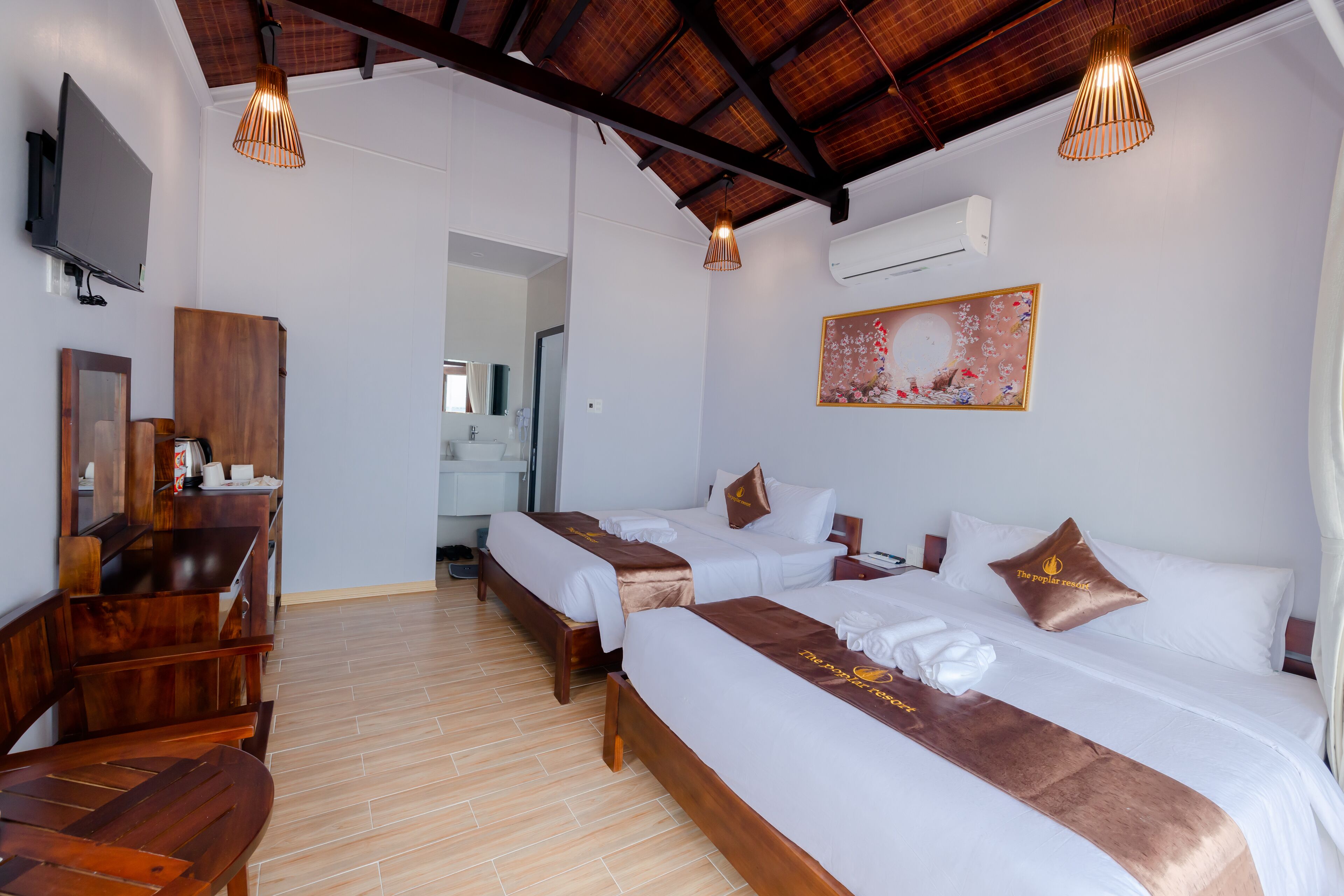 Habitación de hotel con dos camas, muebles de madera, un televisor y un cuadro en la pared.