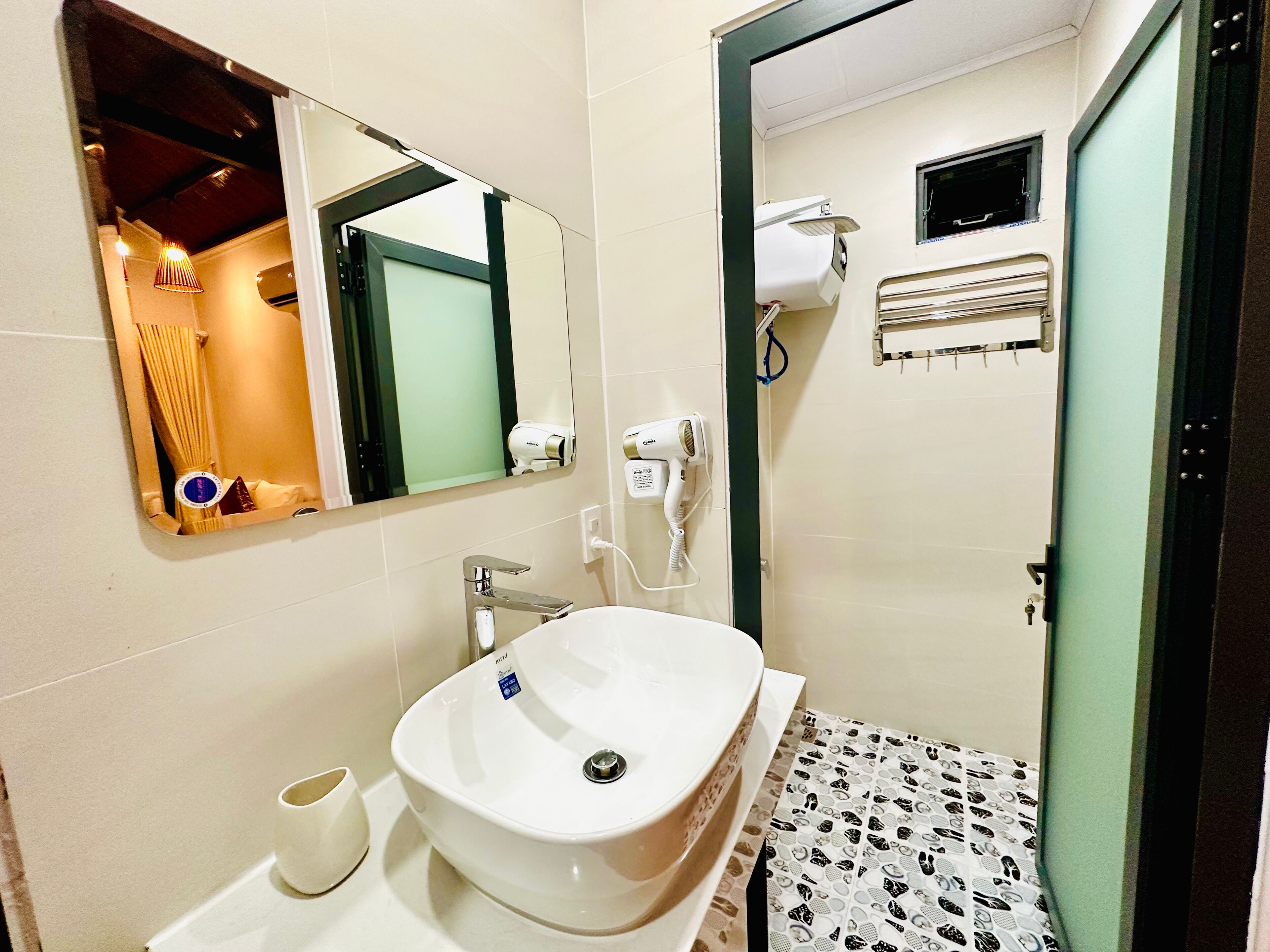 A bathroom with a white sink, a mirror, a hairdryer, and a towel rack.