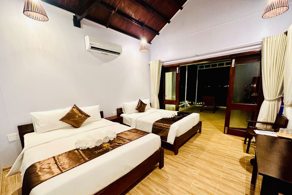 A hotel room with two beds, a desk, and a view of the outside.
