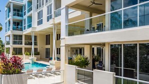 A modern multi-story building with a rooftop pool area, outdoor seating, and large windows. - Coastal Condo Retreat: 3BR 2.5BA w/ Heated Infinity Pool (Deerfield Beach)