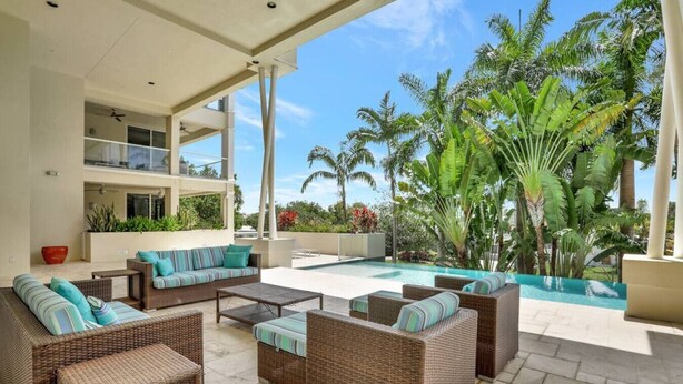 A covered outdoor seating area with wicker furniture and a pool. - Coastal Condo Retreat: 3BR 2.5BA w/ Heated Infinity Pool (Deerfield Beach)