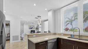 A modern kitchen with a dishwasher, a sink, and a window with blinds. - Coastal Condo Retreat: 3BR 2.5BA w/ Heated Infinity Pool (Deerfield Beach)