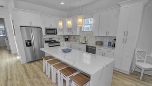 A modern kitchen with white cabinetry, stainless steel appliances, and a central island with bar stools. - Private Heated Pool | FREE Golf Cart | 5 BR Home | 5 Outdoor Spaces | Near Dune Allen Beach (Santa Rosa Beach)