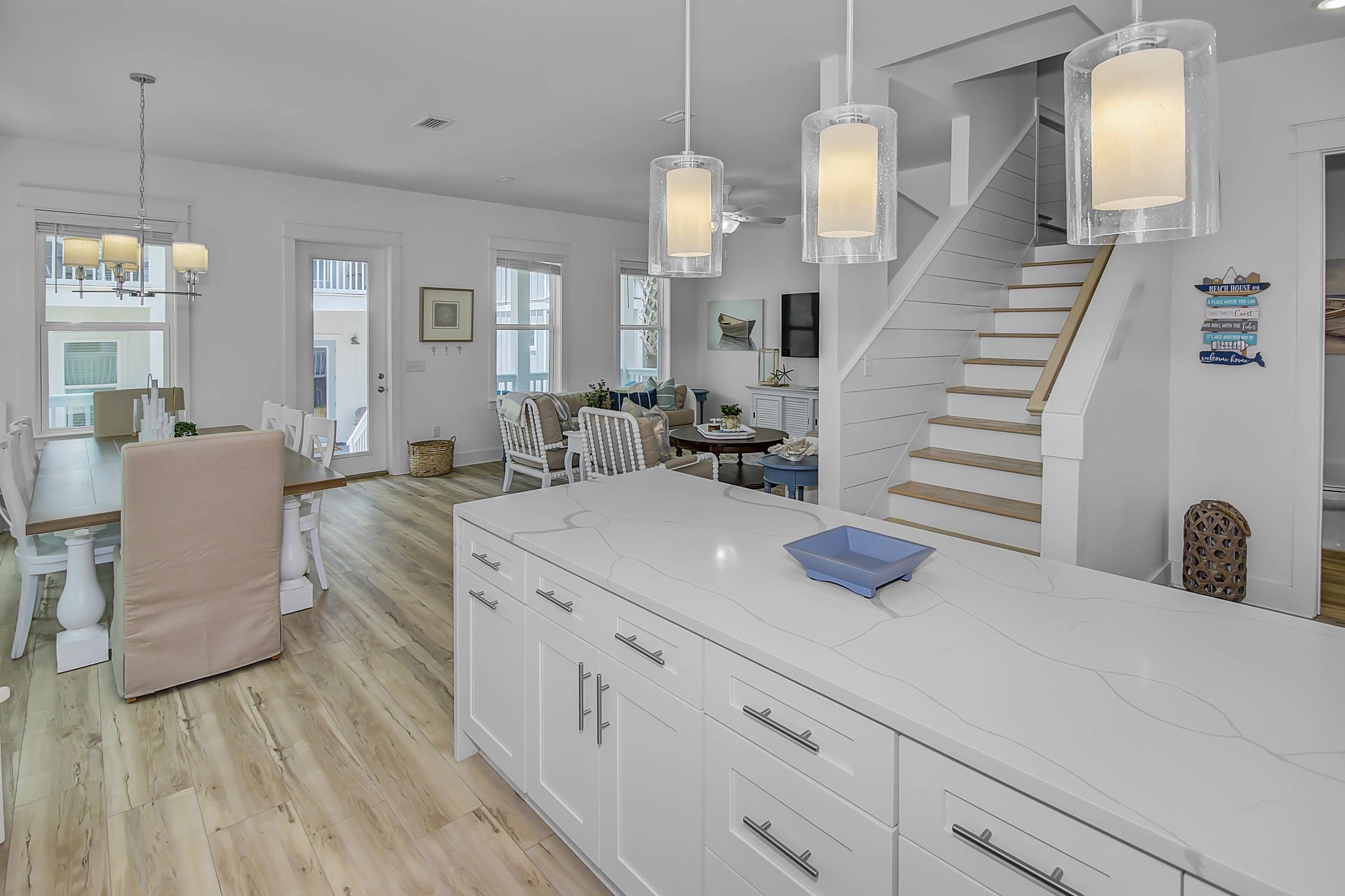 A spacious kitchen with a large island, white cabinetry, and pendant lighting.