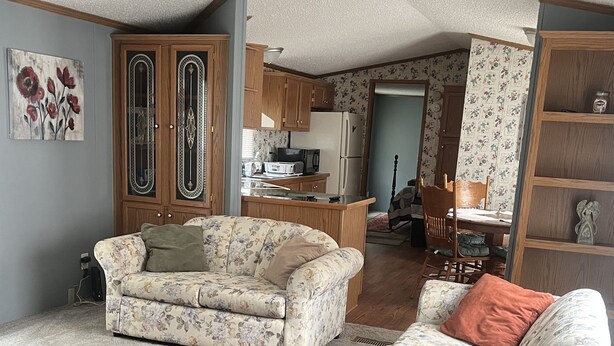 Ein Wohnzimmer mit floral gepolsterten Sofas, einem roten Teppich und Holzschränken.