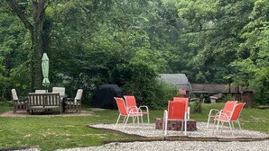 Ein möblierter Patio-Bereich mit Tisch und Stühlen, umgeben von Kies und dichter Bepflanzung.