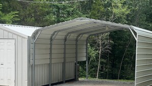 Eine Metallhütte mit geneigtem Dach, einer Tür und einem Kiesgrundstück.