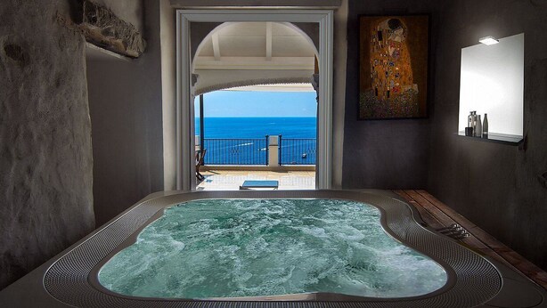 Zona de spa con jacuzzi, vista al mar y un cuadro en la pared.