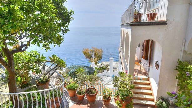 Un balcon orné de plantes en pot, offrant une vue sur la côte.