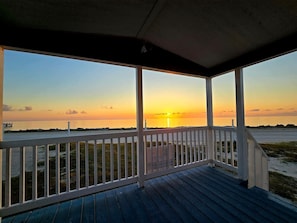 A wooden deck with a railing overlooking a beach at sunset. - Spectacular bay views with access to Lighted Pier (Port Lavaca)
