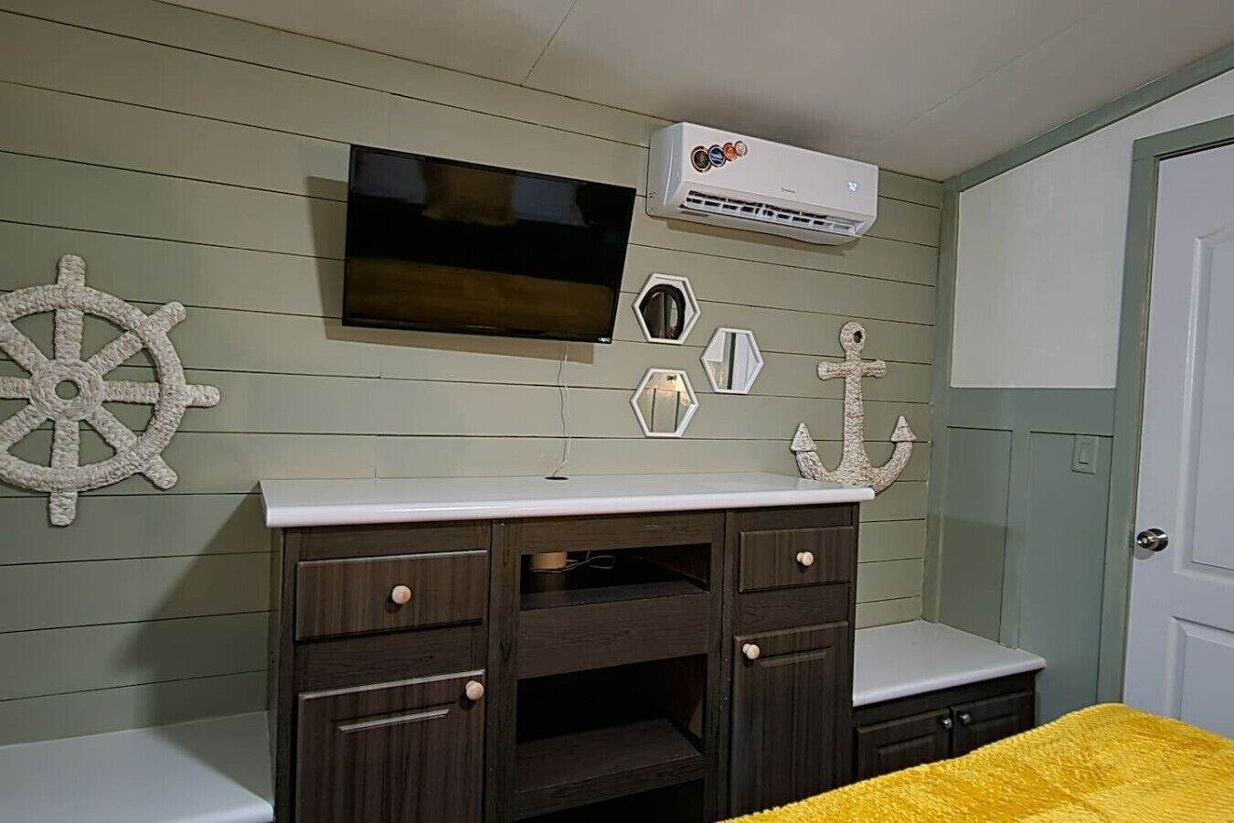 Camera da letto con un letto, una TV, condizionatore d'aria e decorazioni a tema nautico.