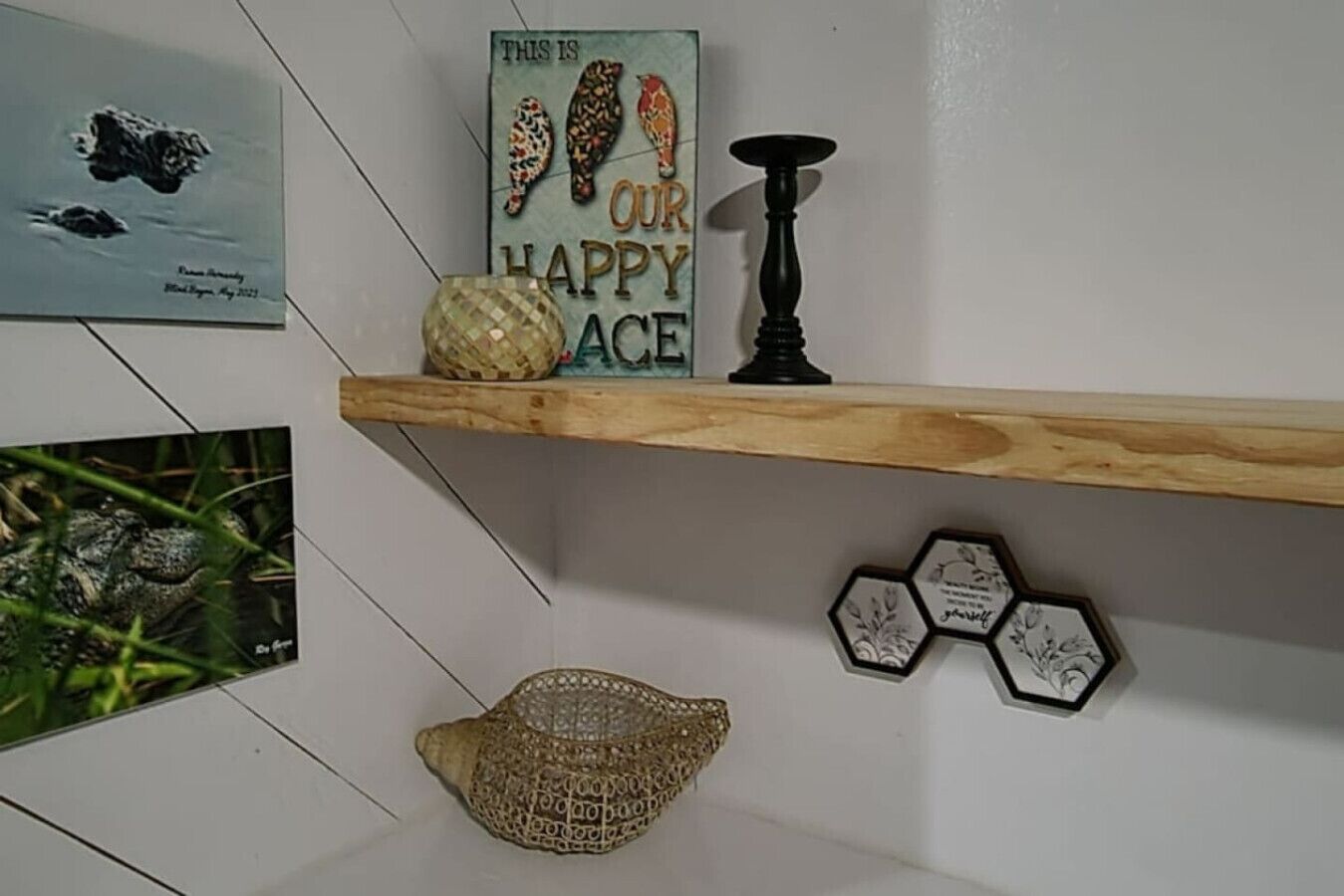 A wooden shelf with decorative items including a sign, a woven basket, and hexagonal wall art.