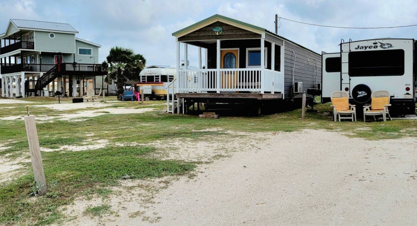 A mobile home with a porch and a Jayco RV parked nearby.