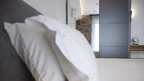 Una habitación de hotel moderna con una cama bien hecha, una pared decorativa de piedra y muebles empotrados.