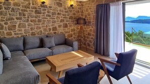 Una sala de estar moderna con una pared de piedra, un sofá, una mesa de centro y vistas al mar.
