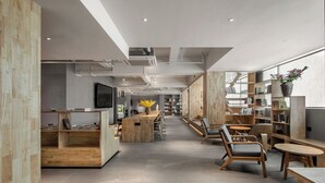 Une bibliothèque moderne, dotée de meubles en bois, d’étagères et d’une table centrale entourée de chaises.