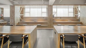 Une salle de réunion moderne, dotée de tables et de chaises en bois, de bibliothèques intégrées et de grandes fenêtres.