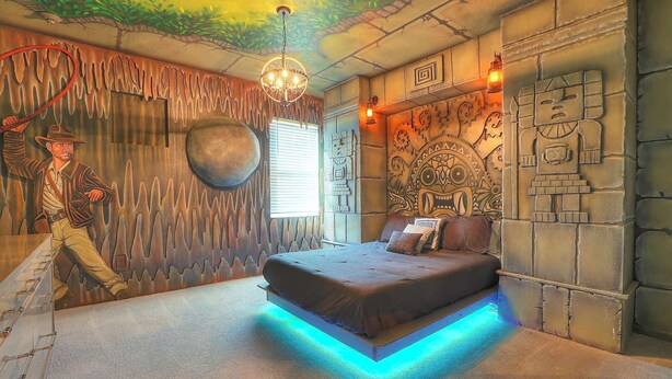 Un dormitorio con una cama, un mural, una araña y una pared de piedra.
