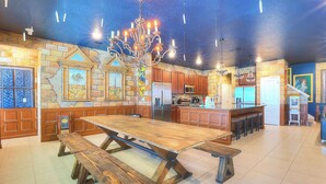 Una cocina amplia con una gran mesa de madera, barra integrada y electrodomésticos modernos.