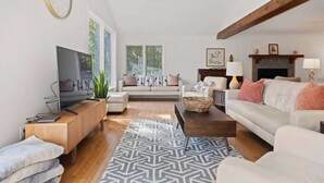 A modern living room with a television, sofa, and fireplace. - Bright 2BR House w/ Sunroom + Fire Pit~Near Trails~Free Tickets (Hendersonville)