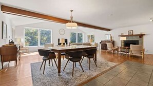 A spacious dining area with a large wooden table, modern chairs, and a hanging light fixture. - Bright 2BR House w/ Sunroom + Fire Pit~Near Trails~Free Tickets (Hendersonville)