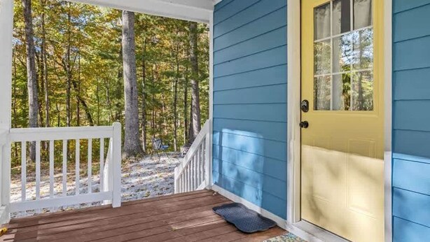 A porch with a white railing, a blue door, and a wooden deck. - Peaceful Woodland Cottage Near Hendersonville (Hendersonville)