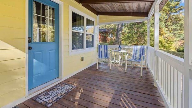A porch with a blue door, a small table, and a chair. - Cozy Woodland 1BR Cottage Near Trails (Hendersonville)