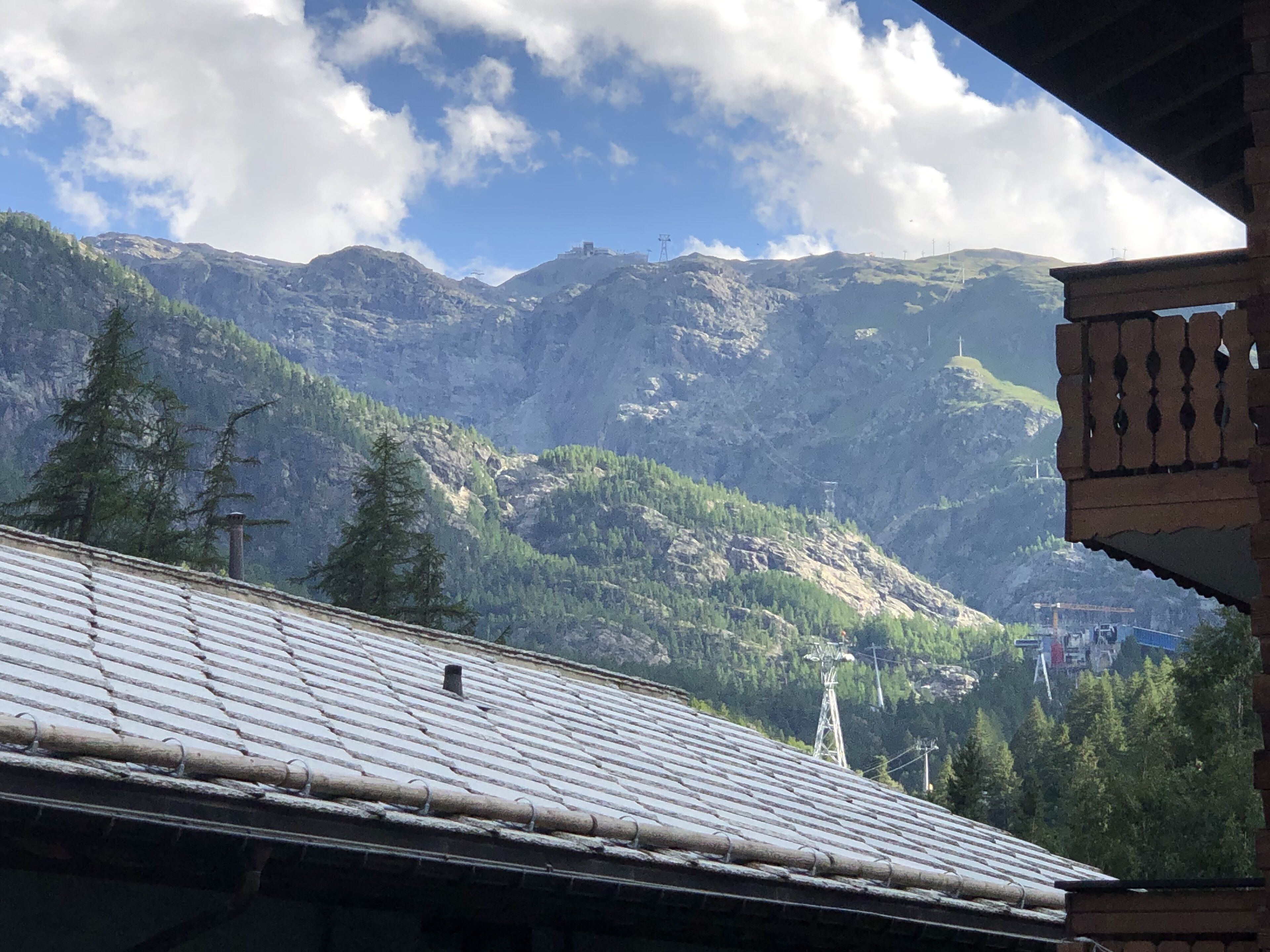 A mountain landscape with a building featuring a tiled roof and a brick wall.