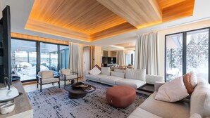 Un salon moderne avec un canapé, des fauteuils, une table basse et un téléviseur.