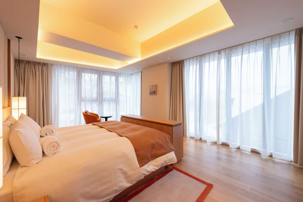 A modern hotel room with a large bed, a desk, and a chair.