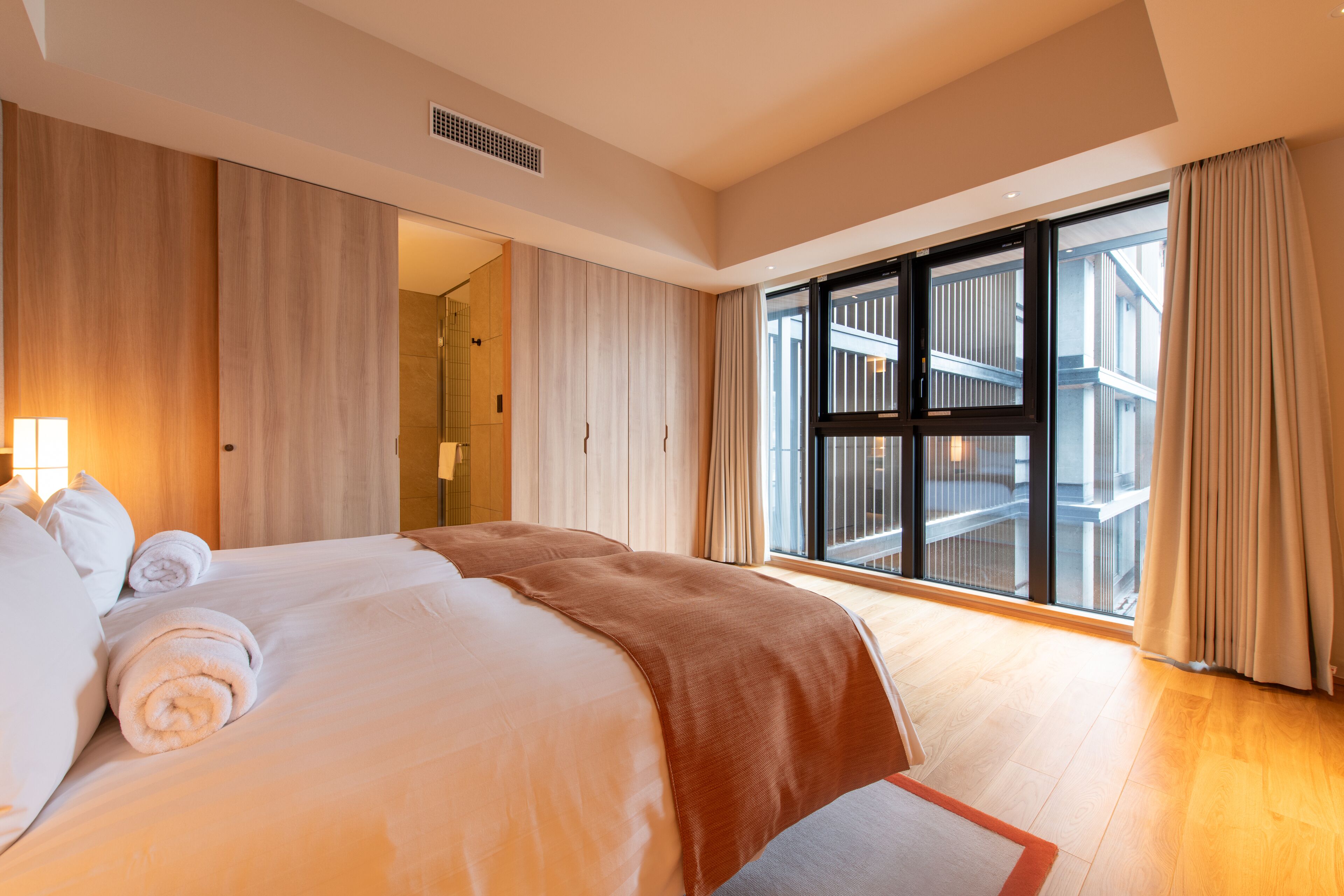Hotelkamer met een groot bed, een schuifglasdeur naar een balkon en uitzicht op de buitenkant van het gebouw.