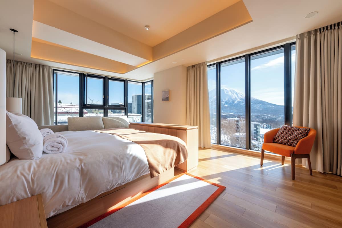 A modern hotel room with a large bed, a desk, and a view of a mountain.
