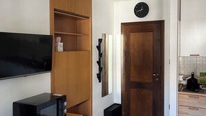 A compact kitchen with a microwave, wooden cabinets, a clock, and a ceiling light fixture. - Cozy Giava's Mountain Place in downtown Aprica (Aprica)