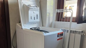 A front-loading washing machine with a control panel, a power outlet, and a label. - Cozy Giava's Mountain Place in downtown Aprica (Aprica)
