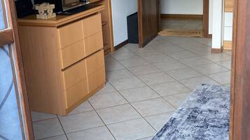 Een kamer met een betegelde vloer, een houten kast, een magnetron, een flatscreen televisie en een deur met sleutelslot.