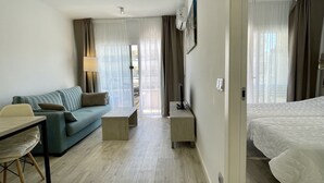 A hotel room with a bed, a sofa, a desk, and a TV. - FESTASTAR 212 (Estartit)