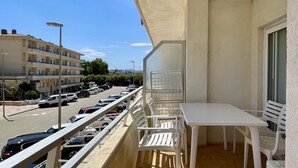 A balcony with a table and chairs, overlooking a parking area and a building with multiple floors. - FESTASTAR 212 (Estartit)