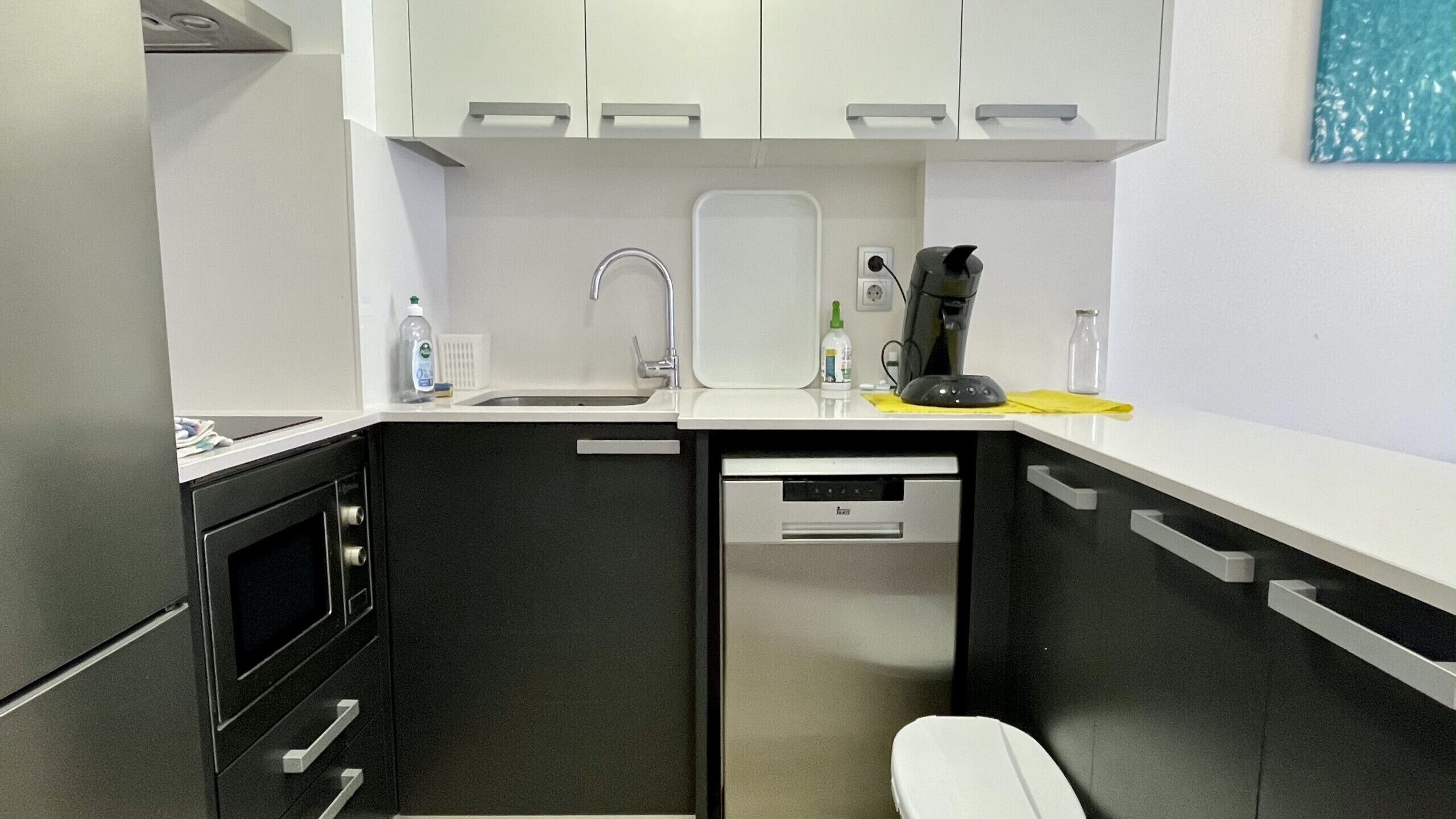 A compact kitchen with a sink, a coffee maker, and a microwave.