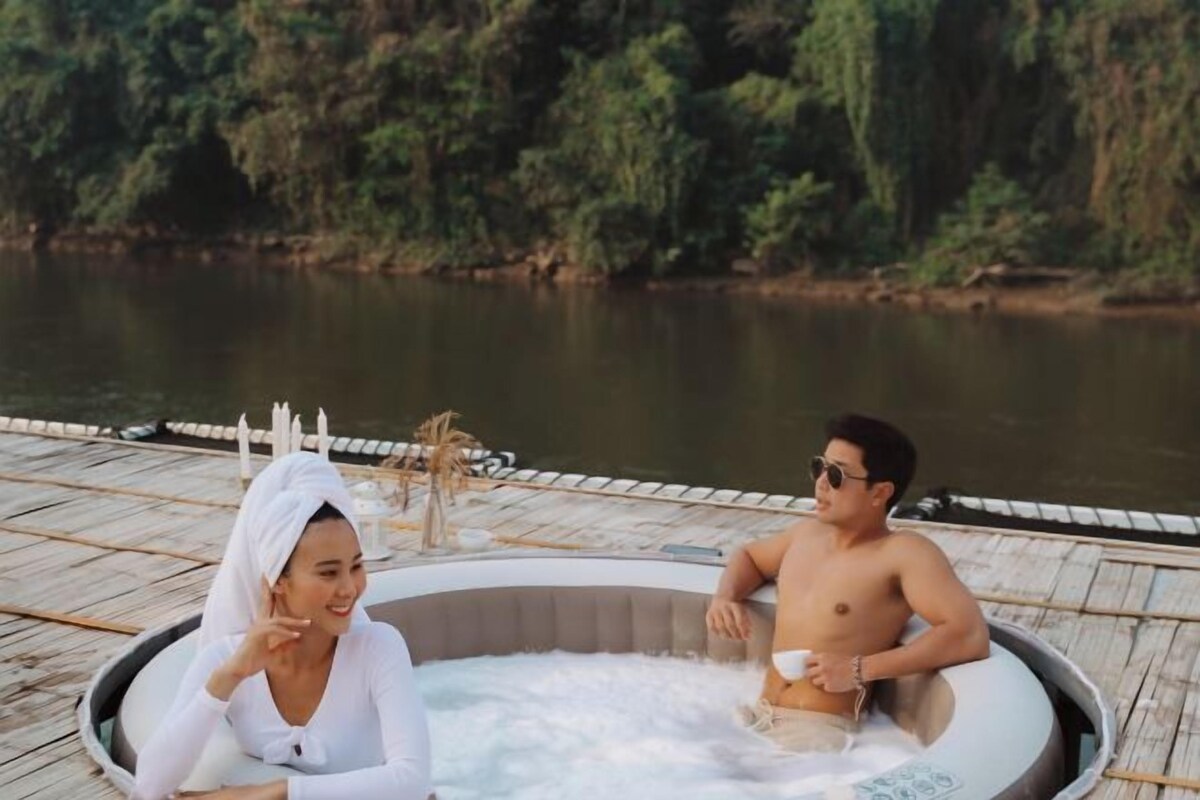 Un jacuzzi en una terraza de madera junto al agua.