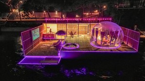 A floating structure with a bar area, seating, and a sheltered sleeping area. - The Three Bubble Houses (Sai Yok)