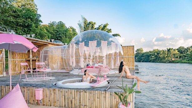 A wooden deck with a hot tub, a transparent dome structure, and a bamboo fence. - The Three Bubble Houses (Sai Yok)