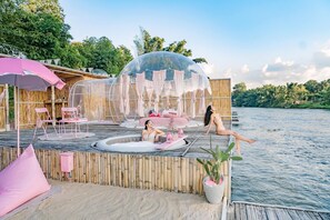 A wooden deck with a hot tub, a transparent dome structure, and a bamboo fence.