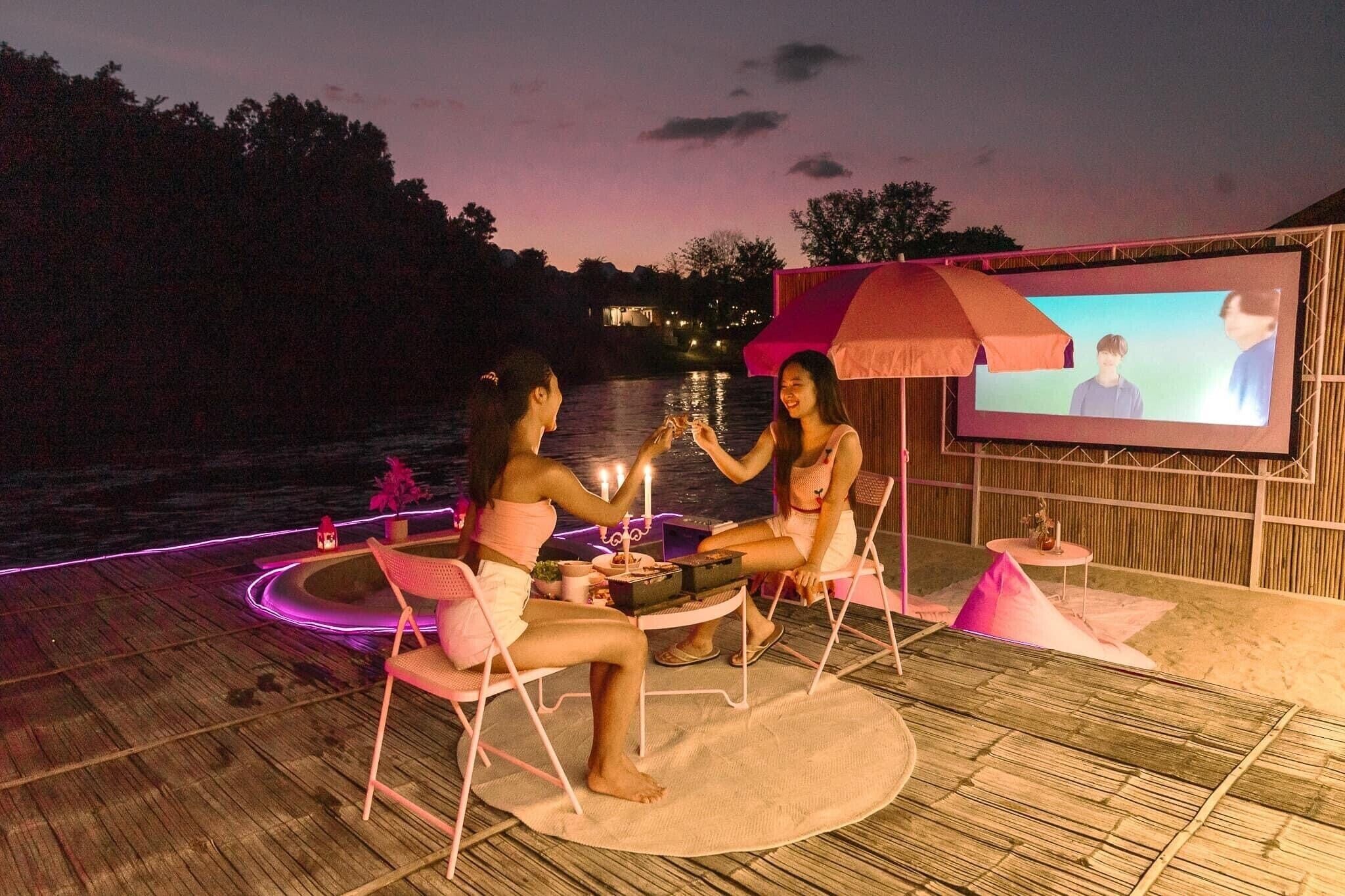 An outdoor seating area with a wooden deck, a round table, and chairs.