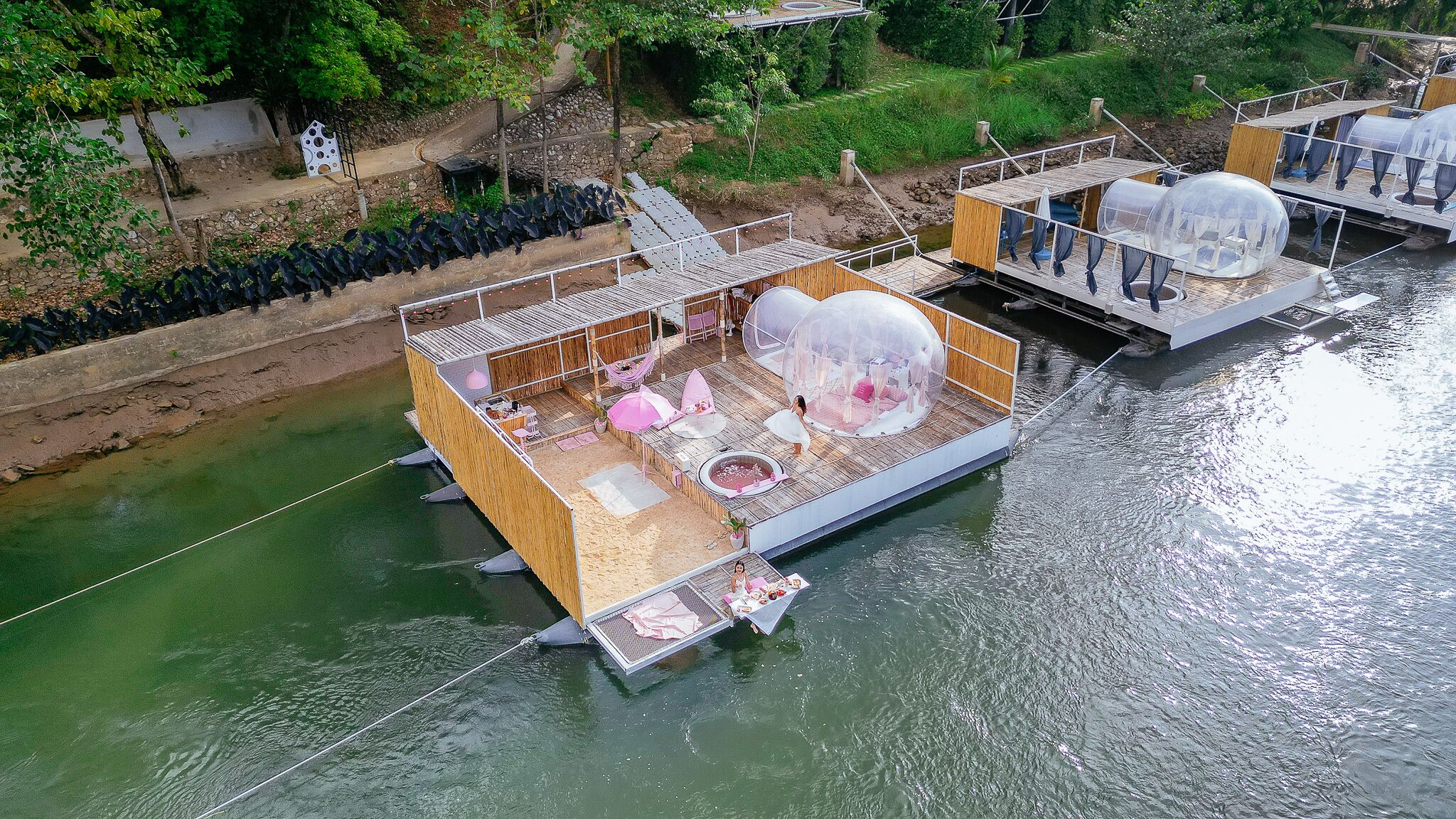 Ein schwimmendes Haus mit Holzterrasse, kleinem Pool und überdachter Sitzgruppe.