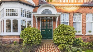 A Victorian-style house with a green door, bay windows, and a tiled pathway leading to the entrance. - Super 1 bed flat in Muswell hill with private garden (London)