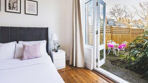A bedroom with a bed, bedside table, lamp, and two framed pictures on the wall. - Super 1 bed flat in Muswell hill with private garden (London)