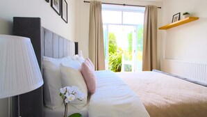 A neatly made bed with white linens and a single pink pillow, a bedside lamp, and a potted orchid. - Super 1 bed flat in Muswell hill with private garden (London)