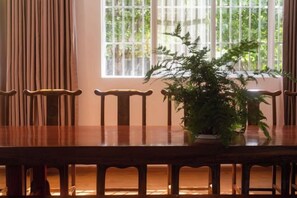 A dining table with chairs, a potted plant, and a window with vertical blinds. - Dali Wenyue Hotel (Erhai Ecological Corridor Branch) (Dali City)