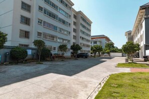 A multi-story building with a parking area and a grassy courtyard.